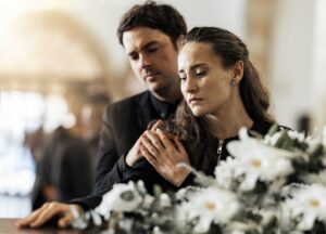 Sad, funeral and flowers with couple and coffin in church for death, respect and mourning. Grief, g